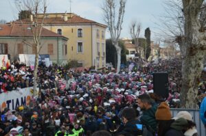 Folla che tiene in mano coni fatti di cartone in cui raccogliere le caramelle che vengono lanciate